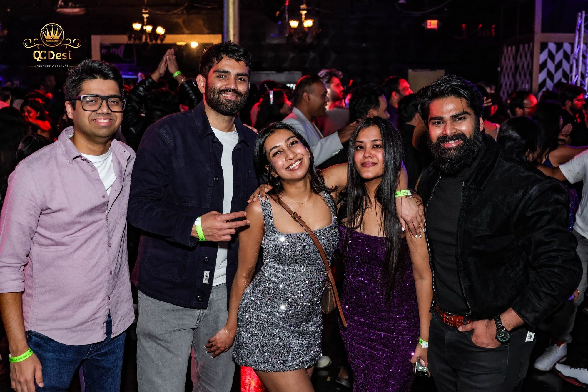 Friends in party outfits posing together at QCDesi New Year's Eve