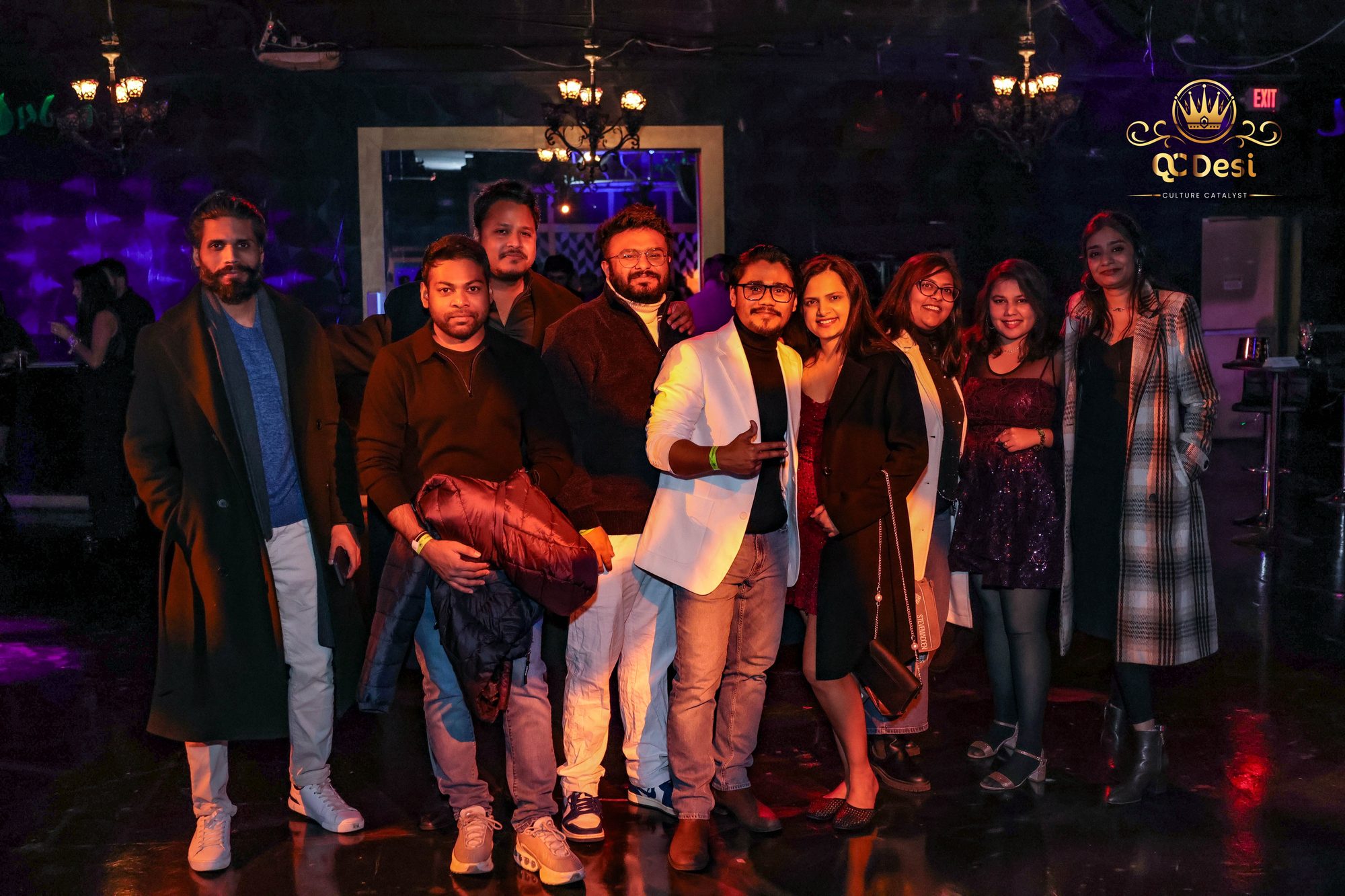 Group of friends posing under the chandeliers at QCDesi New Year's Eve